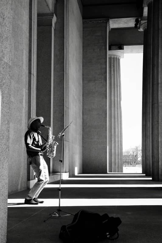Saxophonist busking in a stone colonnade