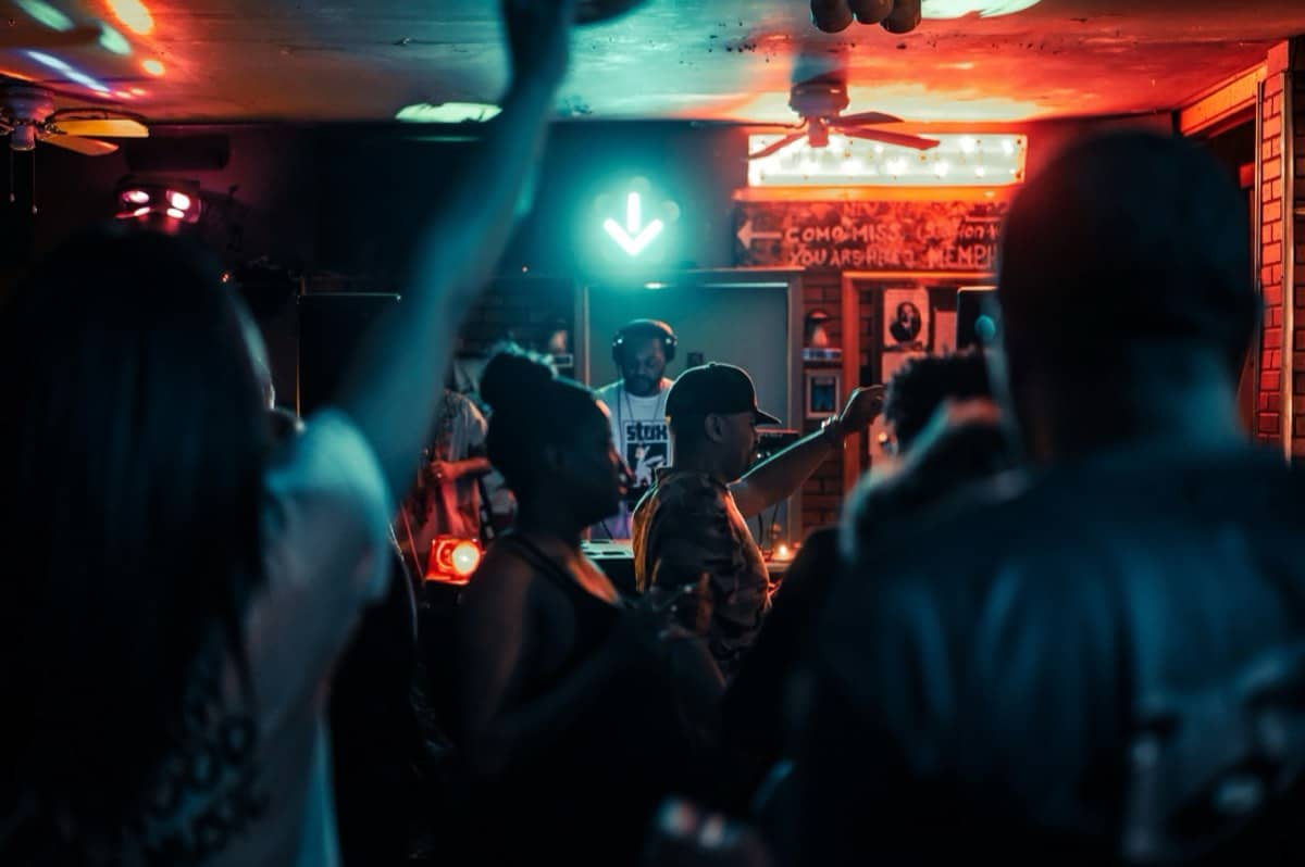 DJ and dancing crowd in a neon-lit bar
