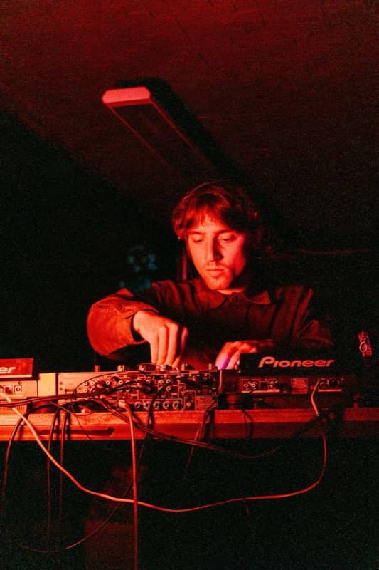 DJ working a mixer under red light